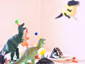 assorted-color dinosaur toys near slice cake on white table