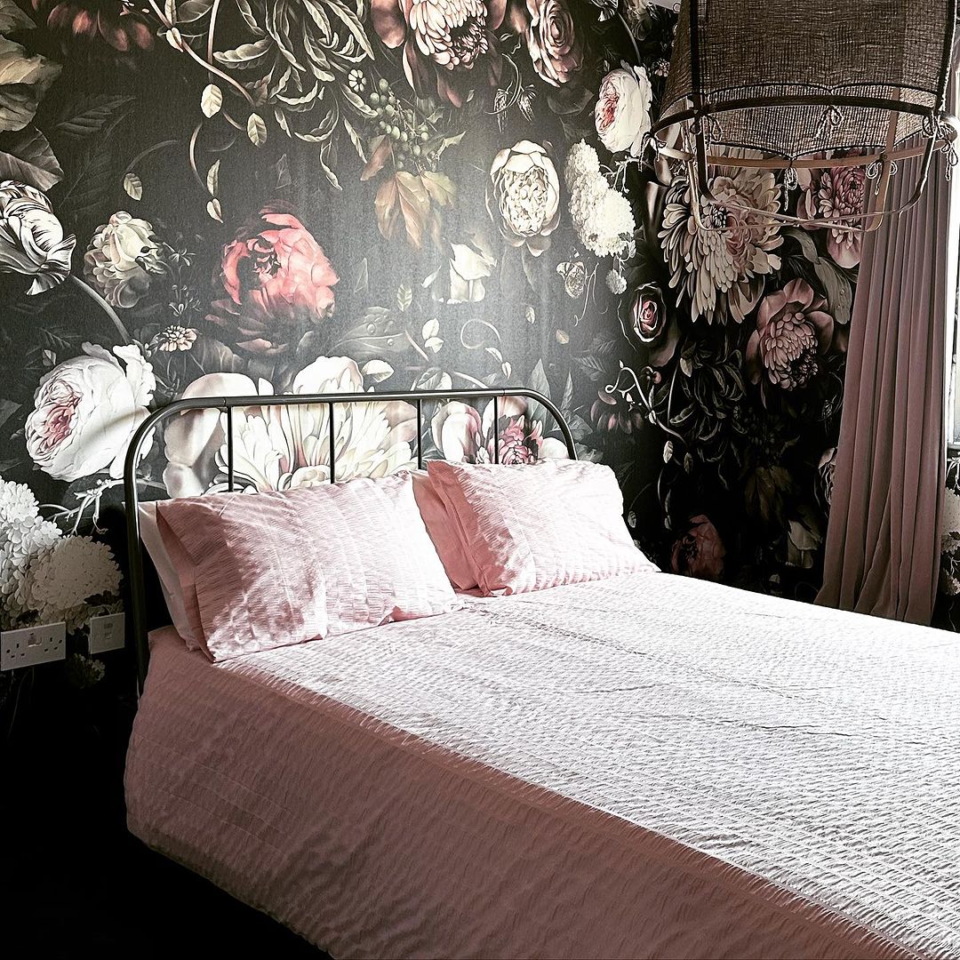 Floral Walpaper With Black Backround, Pink Curtains And Pink Bedding On Quenn Size Industrial Bed