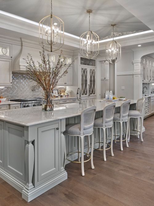 Light Gray Cabinets With White Countertops, Kitchen Island And Chandeliers