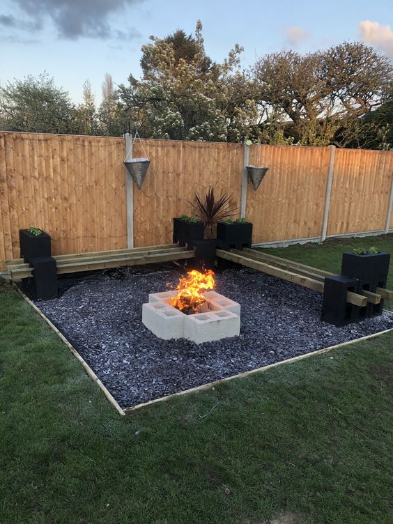 Square Black Gravel Patio With Wooden Benches AndBrick Fire Pit