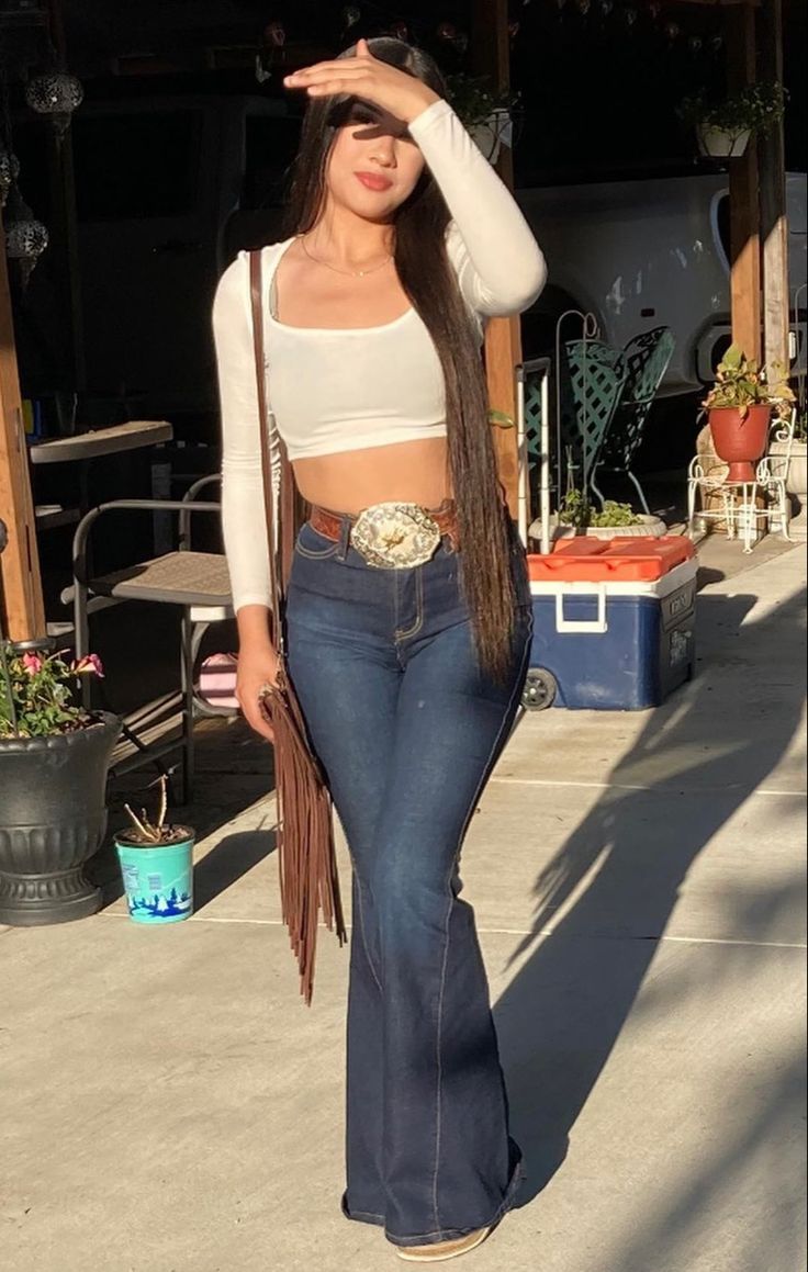 White Long Sleeved Crop Top With Bell Bottom Jeans, Fringed Bag and Large Beltbuckle