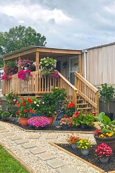 Wooden Porch Surrounded By Colorful Flowers In Flowerbeds And Hanging Planters