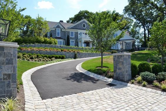 Curved Concrete Driveway With Paver Edges And Stone Pilars