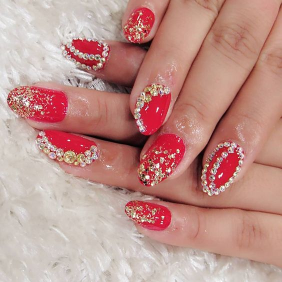 Red Oval Nails With Gold Glitter And Clear Rhinestones