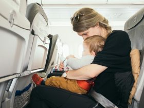 woman carrying baby while sitting on gray seat