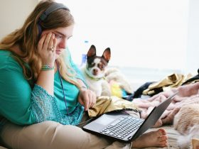 woman in teal long sleeve shirt holding black laptop computer