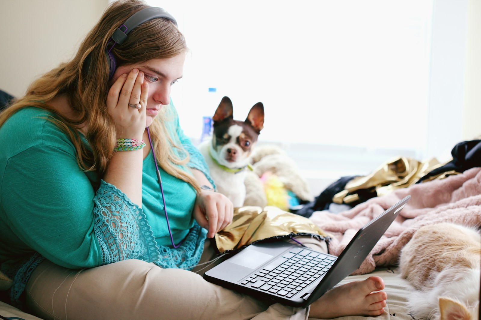 woman in teal long sleeve shirt holding black laptop computer